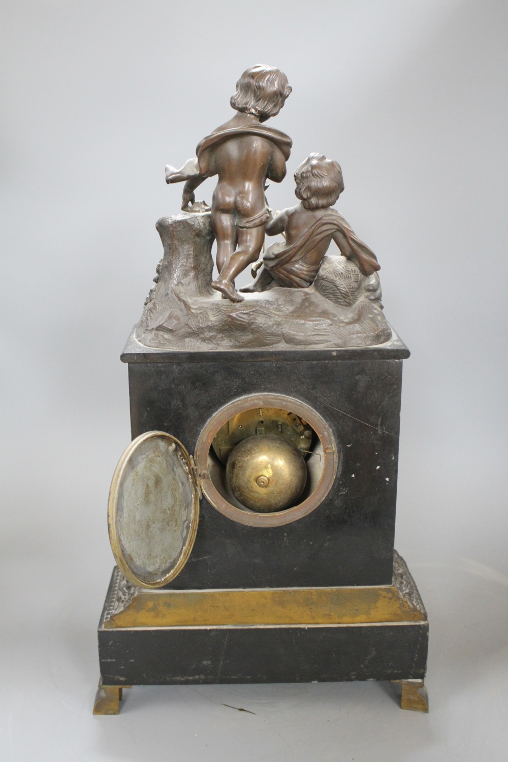 A Victorian bronze mounted black slate mantel clock, with enamelled dial, surmounted with figures of putti, height 48cm